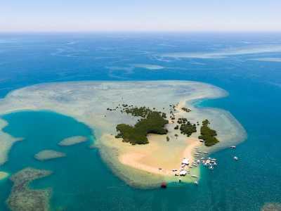 Luftaufnahme einer tropischen Sandbank einer Philippinen Insel mit grünen Mangroven, umgeben von kristallklarem Wasser und mehreren Booten.