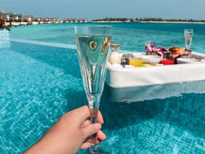 Luxuriöses Frühstück auf einem schwimmenden Tablett in einem Infinity-Pool mit Blick auf das türkisfarbene Meer.