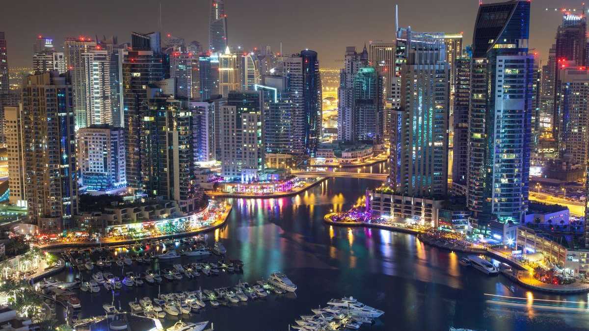 Beleuchtete Dubai Marina bei Nacht mit Yachten, modernen Hochhäusern und lebendiger Atmosphäre