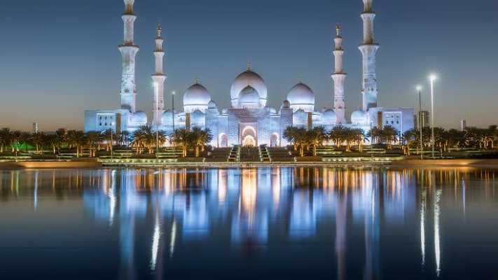 Die Sheikh Zayed Moschee in Abu Dhabi bei Nacht, beleuchtet mit majestätischen Reflexionen im Wasser