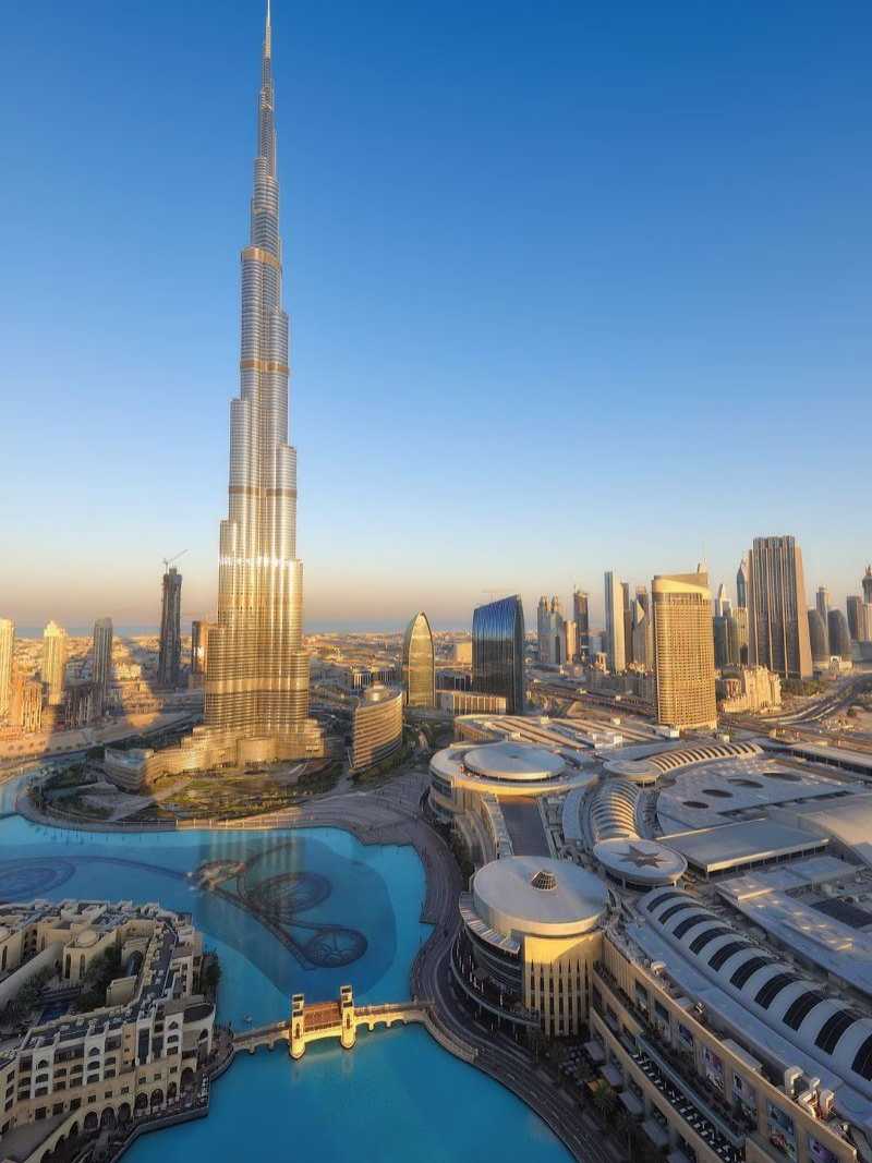 Der Burj Khalifa in Dubai, das höchste Gebäude der Welt, umgeben von modernen Gebäuden und einer türkisfarbenen Wasserlandschaft