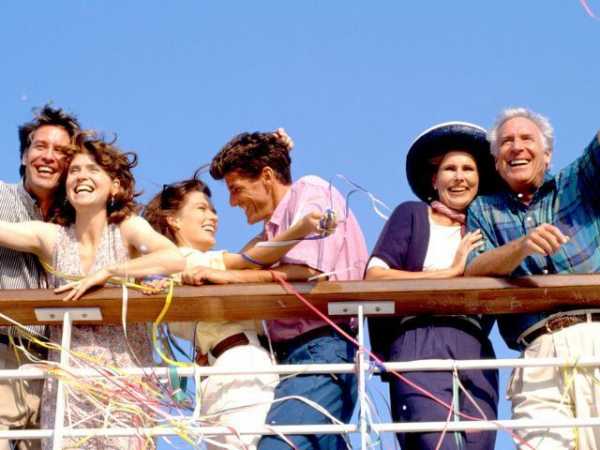 Fröhliche Gruppe von Reisenden auf dem Deck eines Kreuzfahrtschiffs, umgeben von Luftschlangen und blauem Himmel – perfekte Stimmung für eine Minikreuzfahrt.