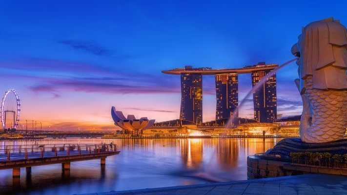 Singapurs ikonische Skyline bei Sonnenuntergang mit dem Merlion-Brunnen, Marina Bay Sands und dem Singapore Flyer