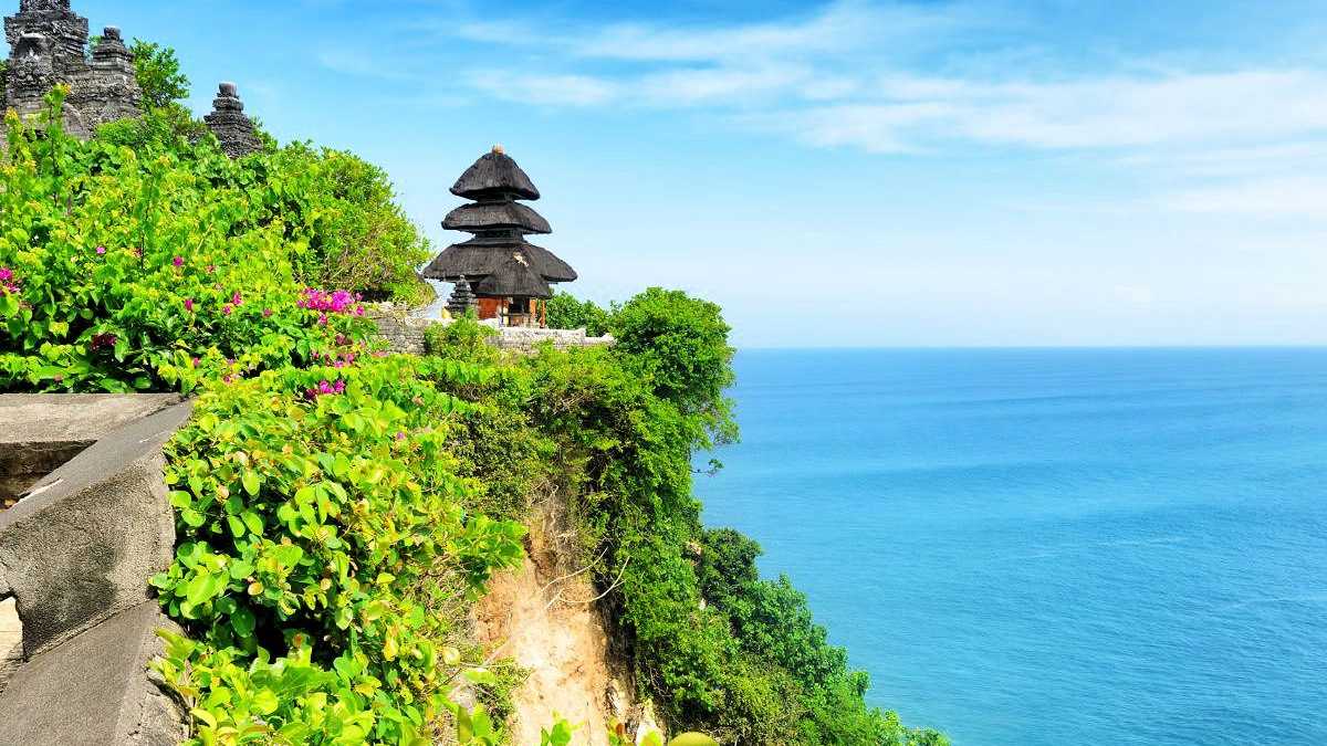 Uluwatu-Tempel auf einer Klippe mit Blick auf das blaue Meer auf Bali, umgeben von üppigem Grün