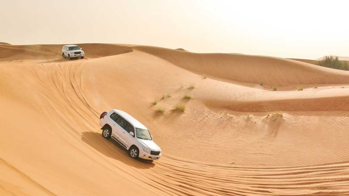 Zwei SUVs bei einer Wüstensafari in den goldenen Sanddünen von Dubai